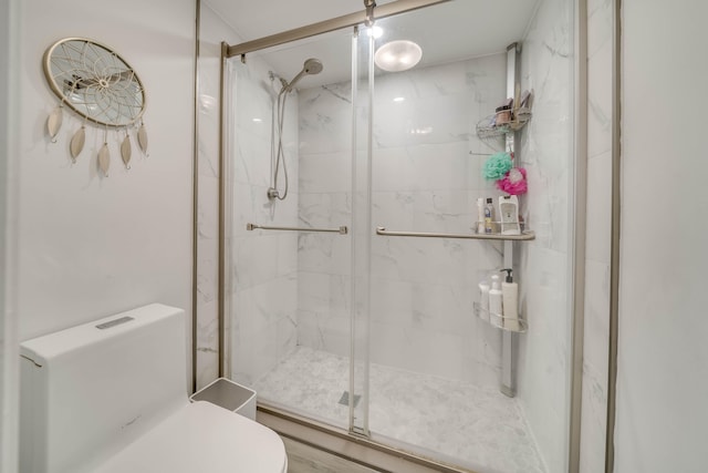 bathroom with a shower with shower door and toilet