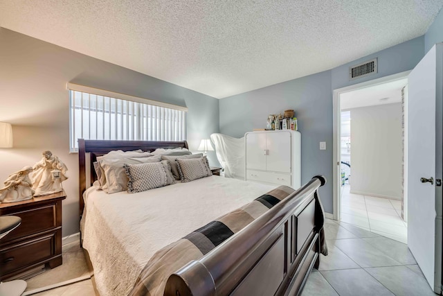 bedroom with a textured ceiling, multiple windows, and light tile floors