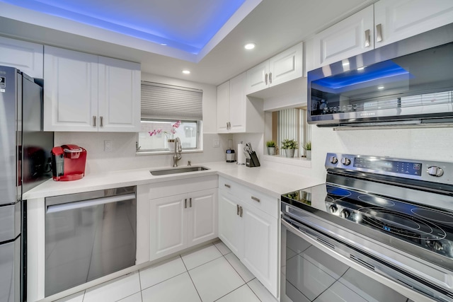 kitchen featuring stainless steel appliances, a tray ceiling, white cabinets, and sink