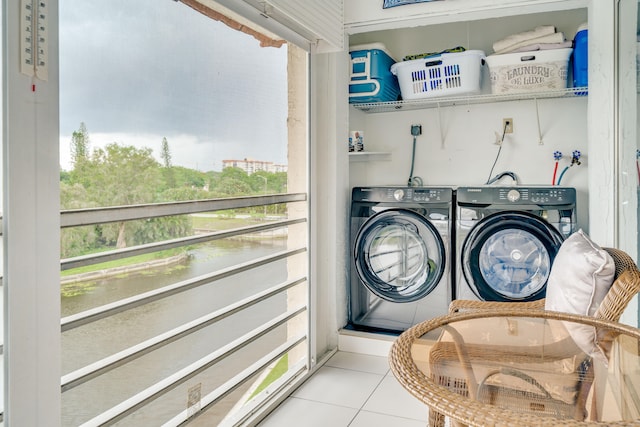 clothes washing area featuring washer hookup, light tile floors, and washing machine and clothes dryer