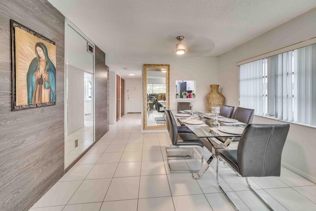 dining space with ceiling fan, light tile flooring, and a textured ceiling