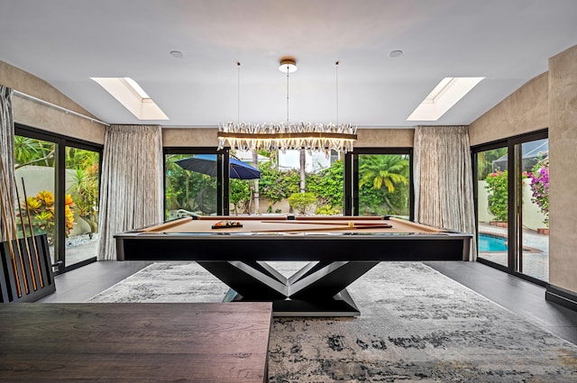 game room featuring vaulted ceiling with skylight, a notable chandelier, a wealth of natural light, and pool table