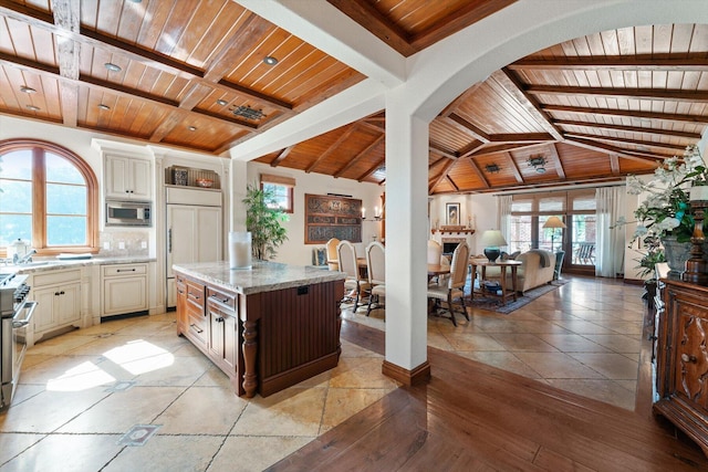 kitchen with a center island, built in appliances, a wealth of natural light, and wooden ceiling