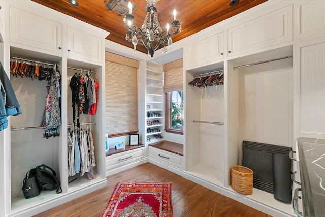 walk in closet with light hardwood / wood-style flooring and a chandelier