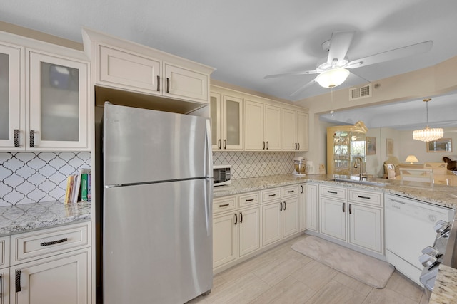 kitchen featuring pendant lighting, decorative backsplash, black electric cooktop, kitchen peninsula, and stainless steel refrigerator