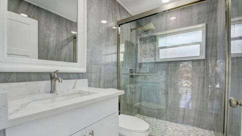 bathroom featuring tile walls, a shower with shower door, large vanity, and toilet