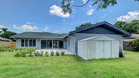 rear view of house featuring a lawn and a storage shed