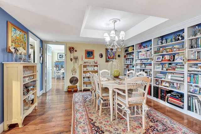 dining space featuring a tray ceiling, hardwood / wood-style floors, and a chandelier