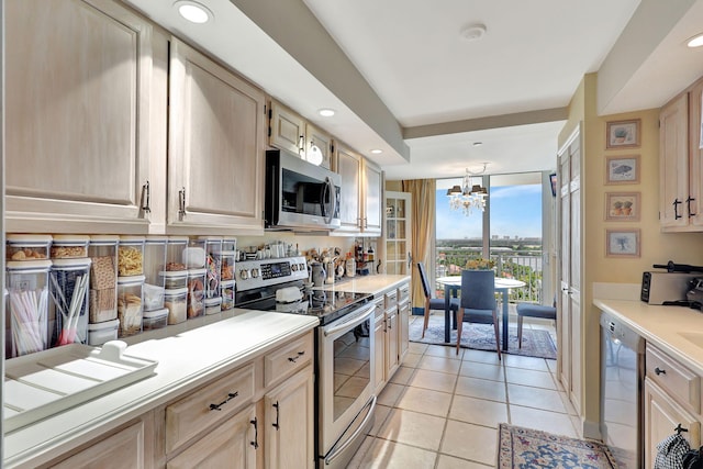 kitchen with light brown cabinetry, pendant lighting, an inviting chandelier, light tile floors, and appliances with stainless steel finishes