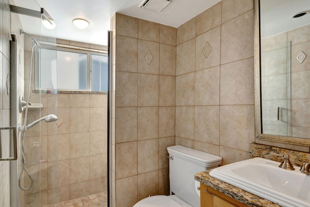 bathroom featuring vanity with extensive cabinet space, an enclosed shower, toilet, and tile walls