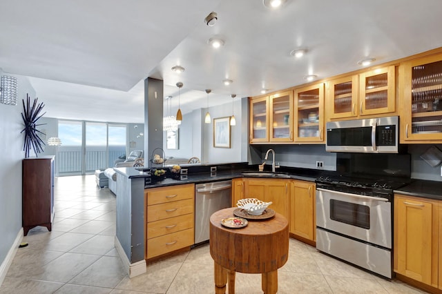 kitchen with appliances with stainless steel finishes, decorative light fixtures, a wall of windows, sink, and light tile flooring