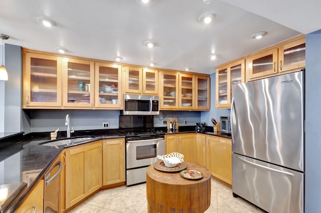 kitchen featuring stainless steel appliances, dark stone counters, pendant lighting, sink, and light tile floors