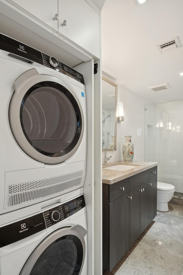 clothes washing area with sink and stacked washer / drying machine