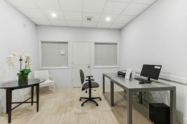 office area with a paneled ceiling and light hardwood / wood-style flooring