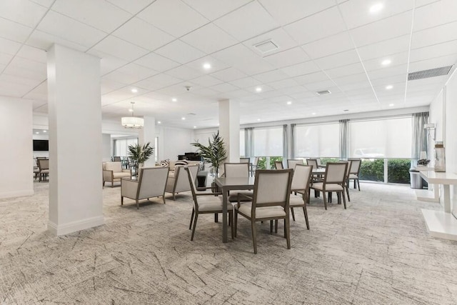 dining area with a paneled ceiling, a chandelier, and light colored carpet