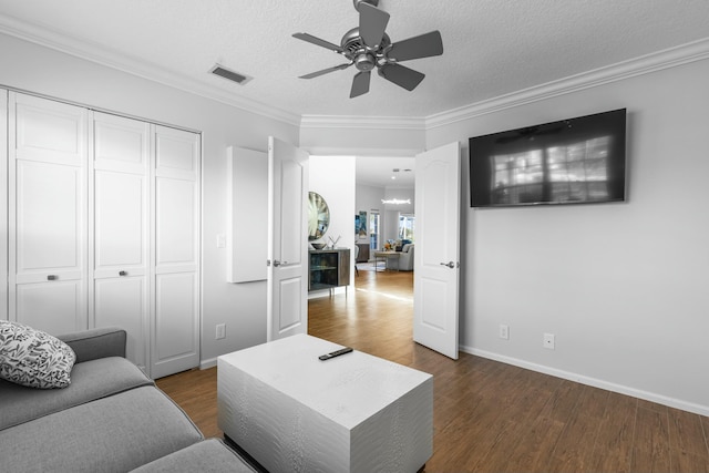 living room with dark wood-type flooring, ceiling fan, ornamental molding, and a textured ceiling