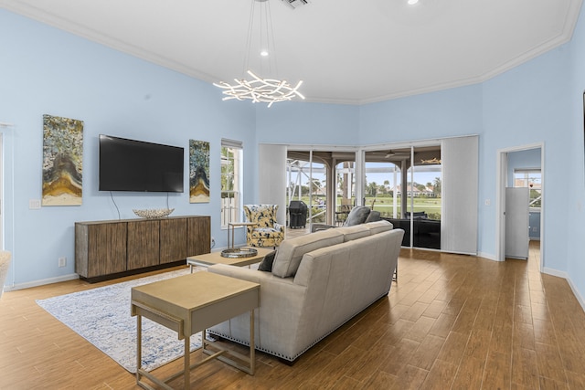 living room featuring a chandelier, wood-type flooring, and crown molding