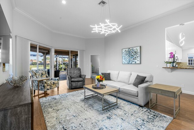 living room featuring hardwood / wood-style flooring, ornamental molding, and a chandelier