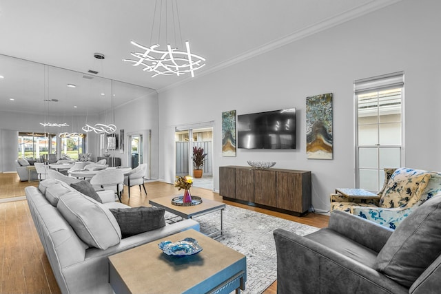 living room featuring crown molding, light wood-type flooring, and an inviting chandelier