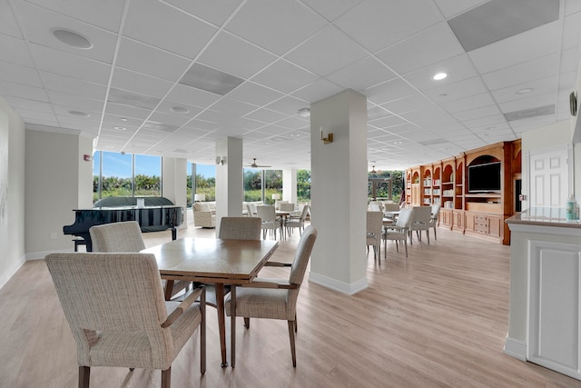 dining space with a drop ceiling, light hardwood / wood-style flooring, and floor to ceiling windows