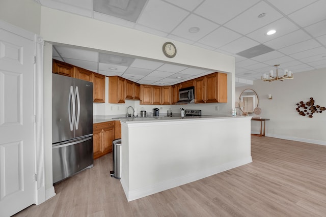 kitchen featuring a paneled ceiling, light wood-type flooring, kitchen peninsula, and stainless steel appliances