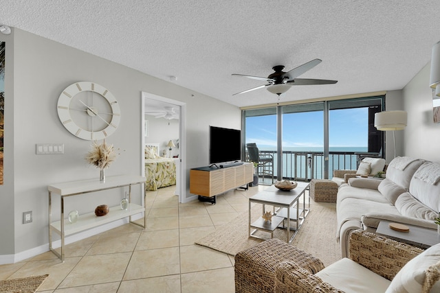 tiled living room featuring floor to ceiling windows, a textured ceiling, a water view, and ceiling fan