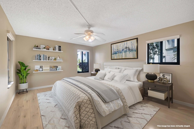 bedroom featuring ceiling fan, light hardwood / wood-style flooring, and a textured ceiling