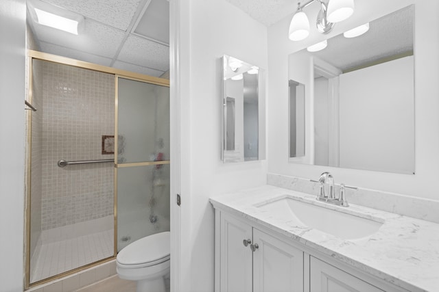 bathroom featuring a shower with door, a paneled ceiling, vanity, and toilet