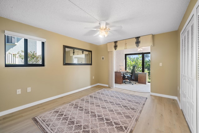 sitting room with a textured ceiling, light wood-type flooring, and ceiling fan