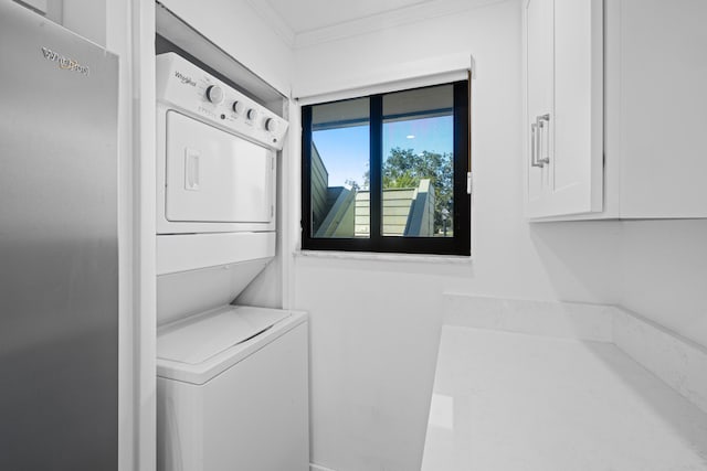 clothes washing area featuring stacked washing maching and dryer and ornamental molding