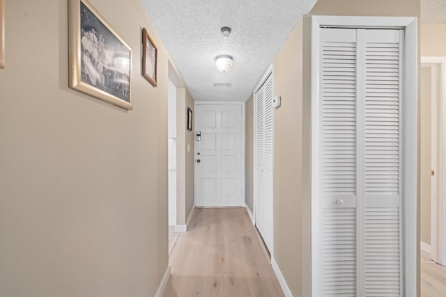 hall featuring a textured ceiling and light wood-type flooring