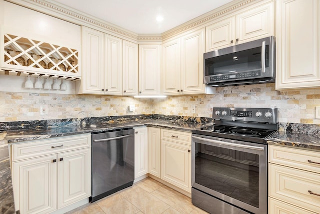 kitchen featuring cream cabinets, dark stone counters, light tile floors, and stainless steel appliances