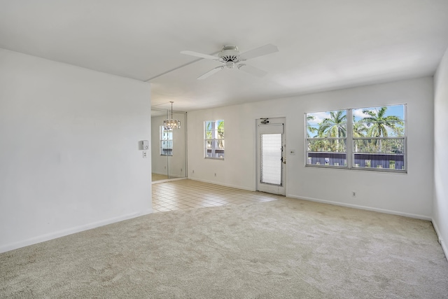 spare room featuring ceiling fan with notable chandelier and light colored carpet