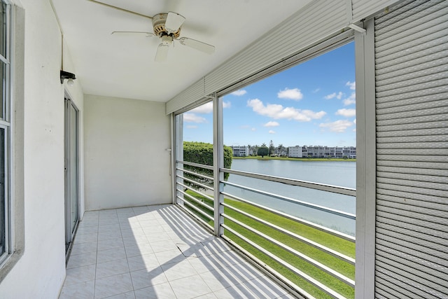 unfurnished sunroom with ceiling fan and a water view