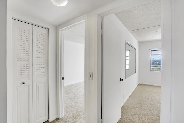 hall with light carpet and a textured ceiling