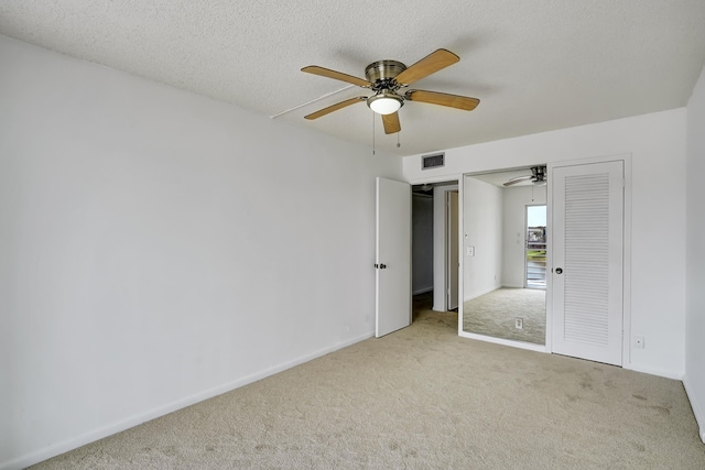 unfurnished bedroom with carpet, a closet, ceiling fan, and a textured ceiling