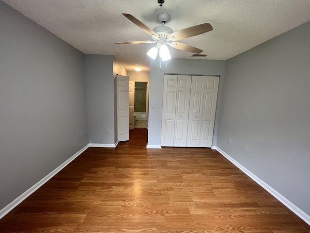 unfurnished bedroom with light wood-type flooring, a textured ceiling, a closet, and ceiling fan