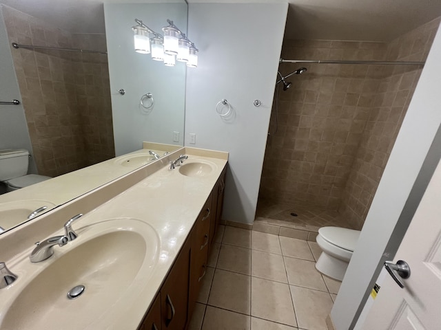 bathroom with tiled shower, tile patterned floors, vanity, and toilet