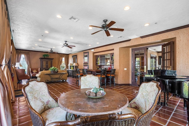 dining room with a textured ceiling, ceiling fan, dark tile patterned floors, and crown molding