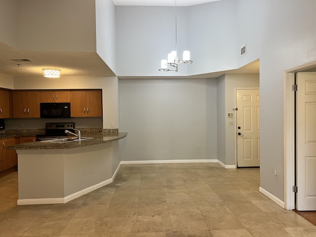 kitchen featuring a notable chandelier, a high ceiling, black appliances, decorative light fixtures, and kitchen peninsula