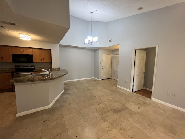 kitchen with stainless steel range with electric cooktop, sink, a towering ceiling, decorative light fixtures, and kitchen peninsula