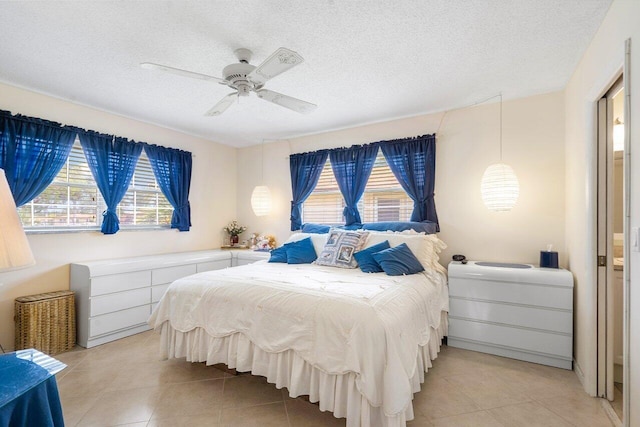 bedroom featuring a textured ceiling, light tile patterned floors, and ceiling fan