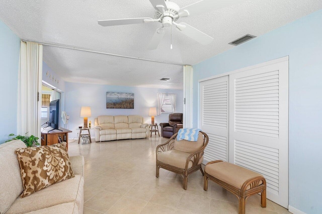 living room with a textured ceiling and ceiling fan