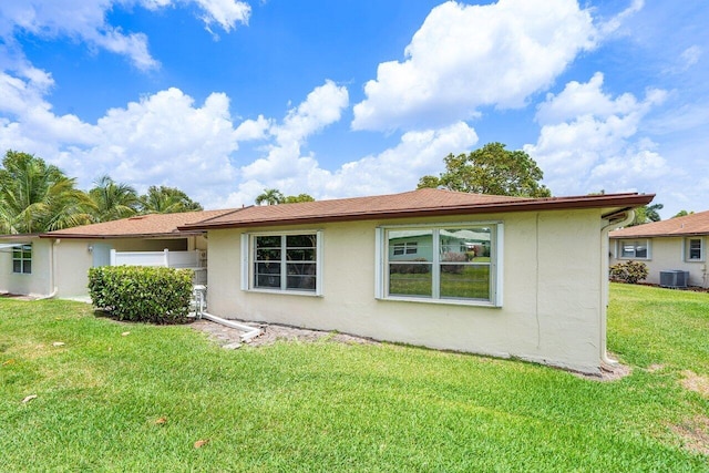 rear view of property with a lawn and central AC unit