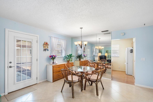 tiled dining space with a textured ceiling and an inviting chandelier