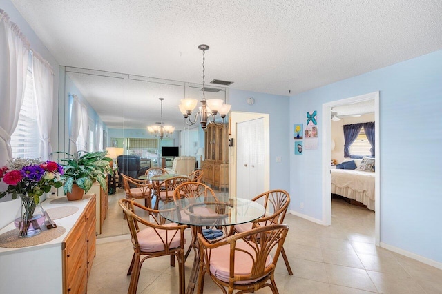 tiled dining room featuring a textured ceiling and ceiling fan with notable chandelier