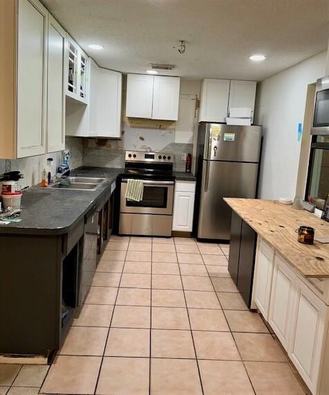 kitchen featuring light tile patterned flooring, white cabinetry, stainless steel appliances, and sink