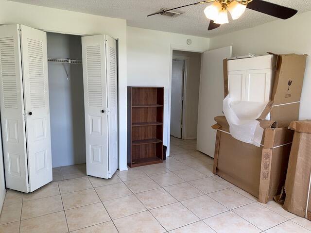 unfurnished bedroom featuring ceiling fan, a textured ceiling, and light tile patterned floors