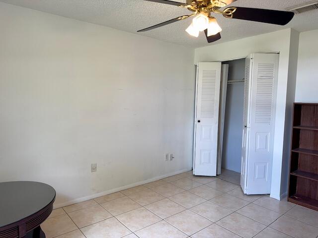 unfurnished bedroom featuring ceiling fan, a textured ceiling, and light tile patterned floors