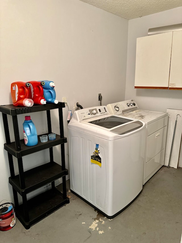 clothes washing area with a textured ceiling, washing machine and dryer, and cabinets